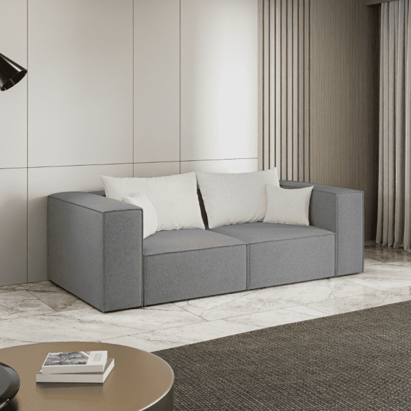 Szara sofa ustawiona w jasnym, nowoczesnym wnętrzu, widok z boku. Inspiracyjne zdjęcie pokazujące stylowe zastosowanie.