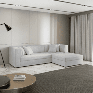 Szara sofa narożna z poduszkami w aranżacji salonu, widok z boku. Zdjęcie przedstawia mebel w nowoczesnej, spokojnej przestrzeni.